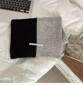 Detail of color-block knit scarf with grey and black patchwork and woven label