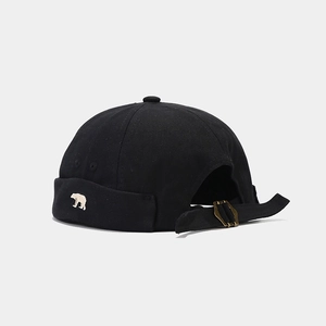 Detail of bear embroidery and metal buckle strap on a black canvas brimless miki hat