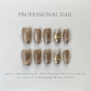 Cat eye press-on nails in coffee gold with yellow rhinestone accents on a display board