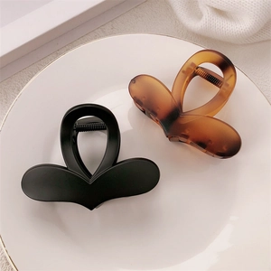Detail of heart hair claws in black and amber shades set on a white ceramic plate