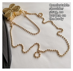 Detail view of mini gold butterfly-shaped metal bag with sleek bead chain strap