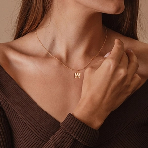 Close-up of gold 'W' letter pendant with pavé crystals on a minimalist bead chain