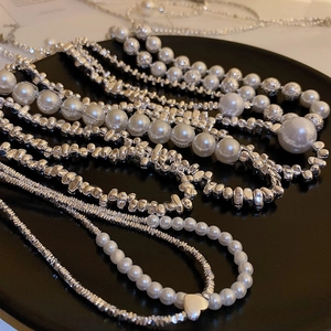 Detail of silver irregular metal beads and white pearls with a heart charm on a tray