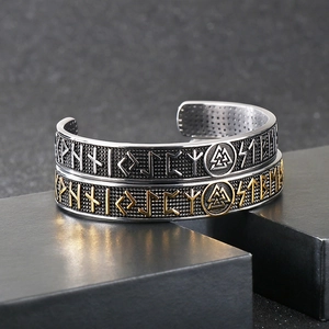 Detailed view of silver and gold Viking rune bangles on a black jewelry display case