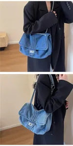 Detail view of a vintage denim chain tote bag worn with a black coat in a minimalist setting