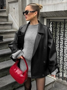 Street style shot of oversized black leather jacket paired with a gray knit dress and red bag