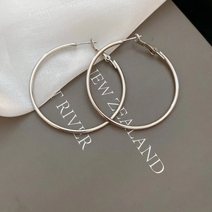 Close-up of minimalist silver hoop earrings on elegant silk fabric and card background