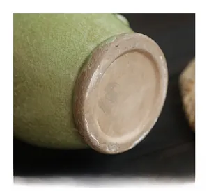 Dettaglio dello smalto crackle su vaso in ceramica verde con base rustica in terracotta