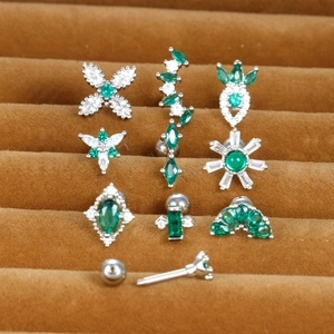 Macro shot of stainless steel screw earrings with green zircon in various floral shapes