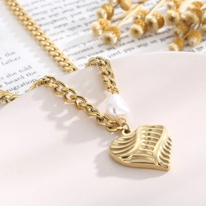 Detail of gold heart pendant necklace with freshwater pearls on a vintage background