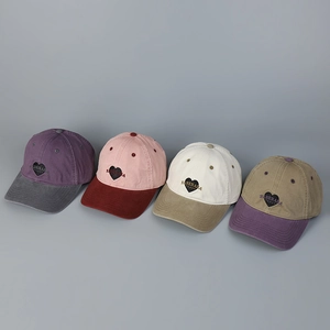 Close-up of four washed cotton baseball caps with heart embroidery and contrast colors