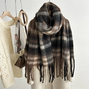 Fashionable oversized striped plaid scarf with tassels styled on a wall hook with outfit