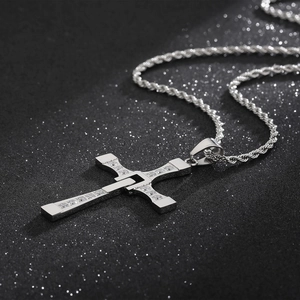 Macro detail of silver cross pendant with inlaid clear diamonds on twist chain