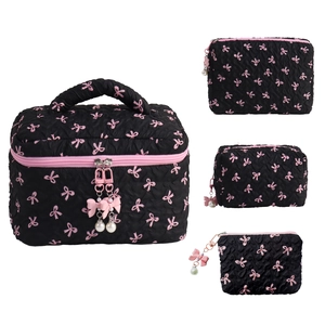 Quilted black makeup bag set with pink bows and pearl zipper charms on white background