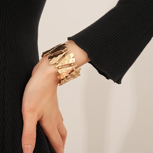 Détail d'un large bracelet manchette doré avec des textures martelées en forme de cœur