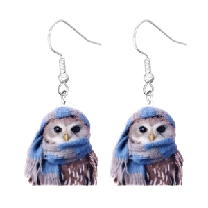 Detail of owl acrylic earrings featuring a brown owl wearing a blue knitted scarf