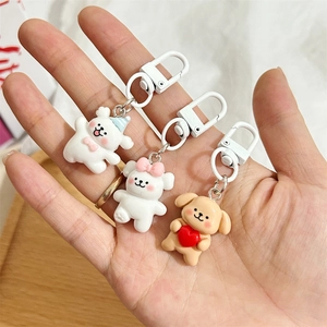Dettaglio di portachiavi a forma di orso e cane con ganci in plastica bianca e cuore rosso