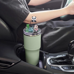 Detailed view of a green tumbler with a cute panda and bamboo topper in a car cup holder