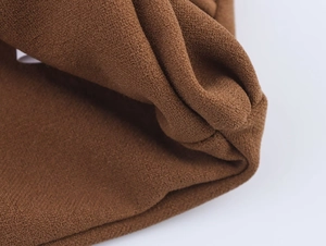Vue macro montrant le tissu marron texturé et les détails plissés de l'ensemble jupe