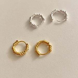 Macro shot of twisted rope texture hoop earrings in polished gold and silver finish