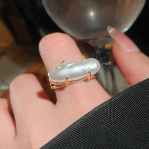 Close-up of irregular baroque pearl ring with golden four-prong setting on hand