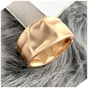 Macro detail of gold textured cuff bracelet showing hammered metal finish and wide open design