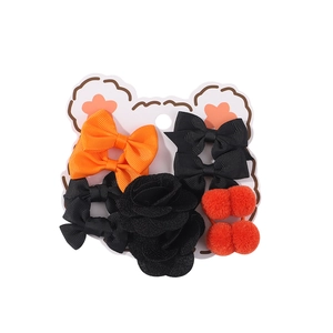Dettaglio set di fermagli per capelli bimba con fiocchi arancioni e fiori neri su carta