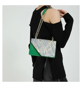 Detail of green and silver textured handbag with golden chain strap on a fashion model