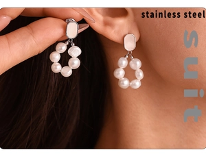 Close-up of pearl hoop earrings on model featuring polished stainless steel details
