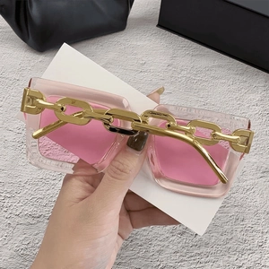 Detalle de gafas de sol rosa con patillas de cadena dorada extragrandes