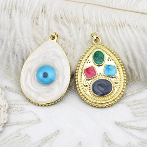 18K gold plated evil eye charms with colorful gemstones on white feathers and lace background