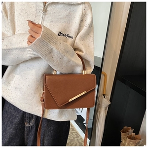 Detailed view of the brown textured leather handbag with gold metal hardware and flap