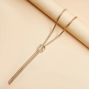 Close-up of golden snake chain necklace with a creative knot design on a beige display