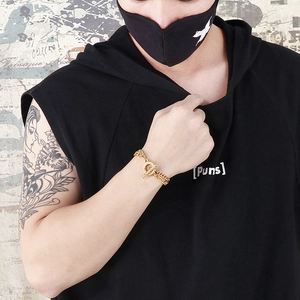 Macro view of gold double chain bracelet with OT clasp on wrist in urban streetwear style