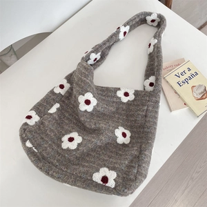 Vista dall'alto di una borsa tote in maglia grigia con motivi floreali e libri lifestyle