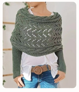 Detail view of a green knit shawl featuring intricate hollow patterns and ribbed cuffs