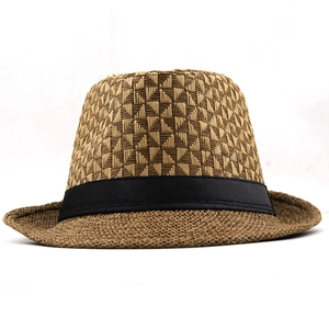 Detail of geometric woven texture and black ribbon band on a breathable straw fedora hat