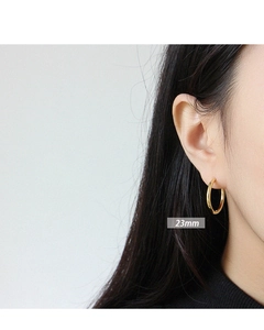 Detail of 23mm golden S925 sterling silver hoop earrings worn by a model