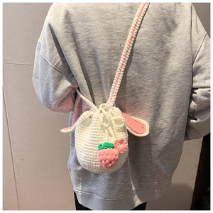 Detail of handmade crochet bunny ear bucket bag with strawberry decor on model's back