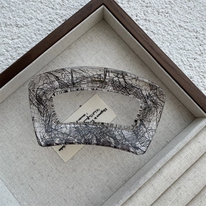 Close-up of a large transparent acrylic hair claw clip with elegant black lace mesh patterns