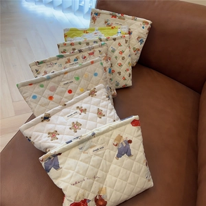 Group of cute bear and floral quilted cotton makeup bags stacked on a leather sofa