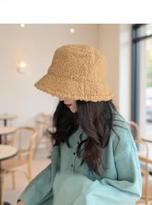 Detail of warm camel faux lamb wool bucket hat with Hello label on a mint green knitwear