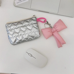 Detail of silver heart-quilted pouch with pink fabric bow charm and zipper closure