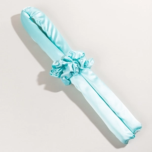 Detail of cyan silk heatless hair curler with matching scrunchie on beige background