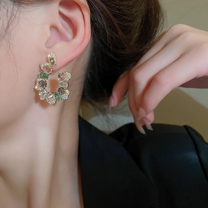 Primo piano di orecchini a U con zirconi colorati indossati da una modella elegante