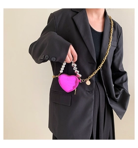 Détail du mini sac cœur rose avec poignée en perles et chaîne dorée sur mannequin