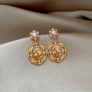 Macro shot of vintage gold flower earrings with pearls and ginkgo leaf relief