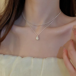 Detail of silver double-layered necklace with irregular pearl pendant on model neck