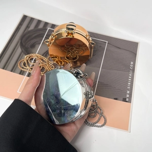 Macro shot of silver and gold mini cylindrical mirror bags with metal ball chains