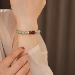 Detail of jade and agate beaded bracelet featuring green stones and golden accents